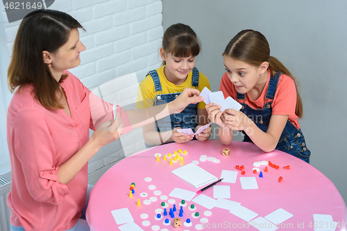 Image of Mom chooses a card from the girl\'s hand, the girl is surprised at the choice