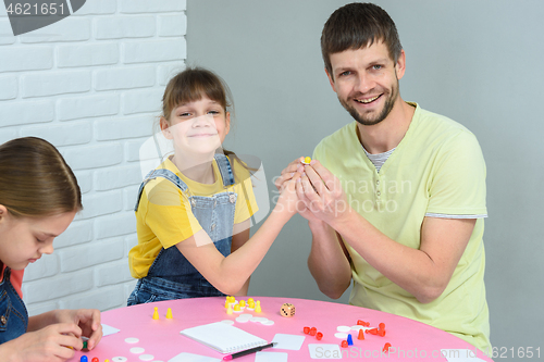 Image of Girl and dad hold chips while playing a board game