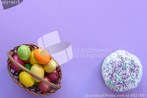 Image of Top view on basket with easter eggs and on cake, purple background