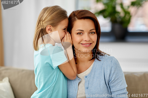 Image of daughter whispering secret to mother at home