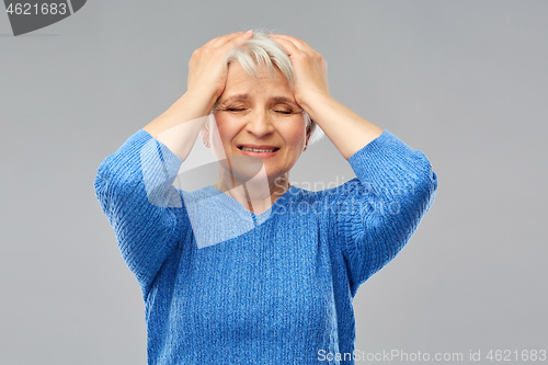 Image of stressed senior woman holding to her head
