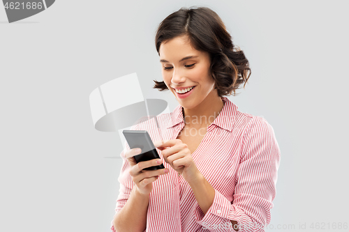 Image of young woman in striped shirt using smartphone