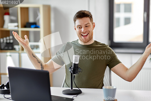 Image of man with laptop and microphone at home office