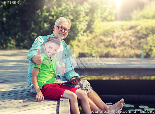 Image of grandfather and boy with tablet pc on river berth