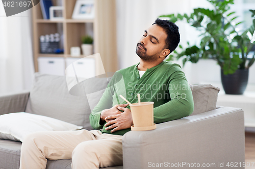 Image of pleased indian man eating takeaway food at home