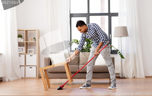 Image of man with broom cleaning floor at home