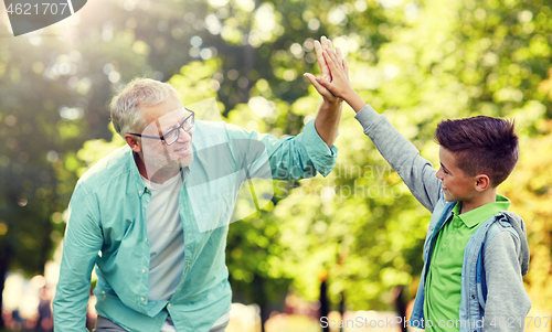 Image of old man and boy making high five at summer park