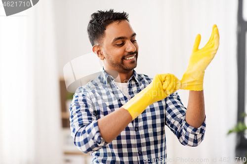 Image of indian man putting protective rubber gloves on