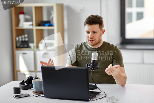 Image of man with laptop and microphone at home office