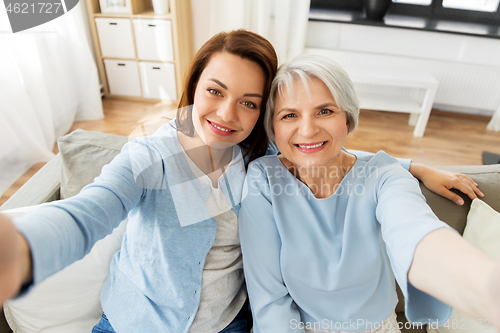 Image of senior mother and adult daughter taking selfie