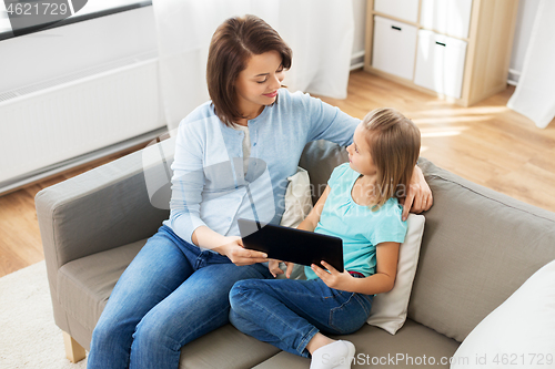 Image of happy mother and daughter with tablet pc at home
