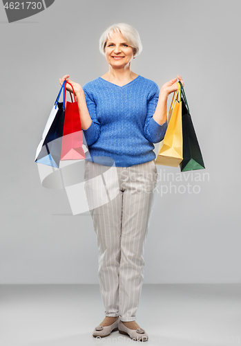 Image of senior woman with shopping bags over grey