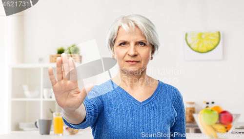 Image of senior woman making stop gesture in kitchen