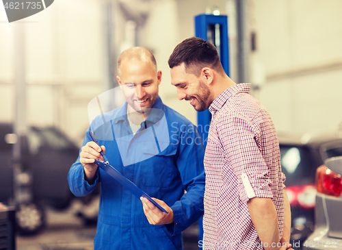 Image of auto mechanic with clipboard and man at car shop