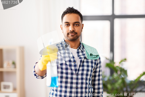 Image of smiling indian man with detergent cleaning at home