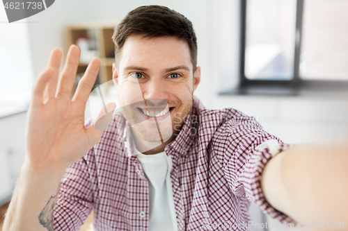 Image of man or video blogger taking selfie and waving hand