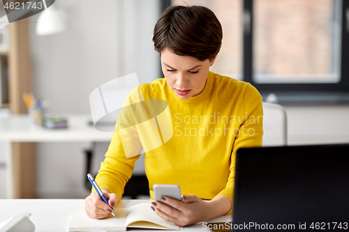 Image of businesswoman with smartphone and notebook