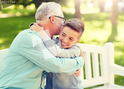 Image of grandfather and grandson hugging at summer park