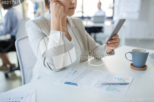 Image of businesswoman with earphones and smartphone