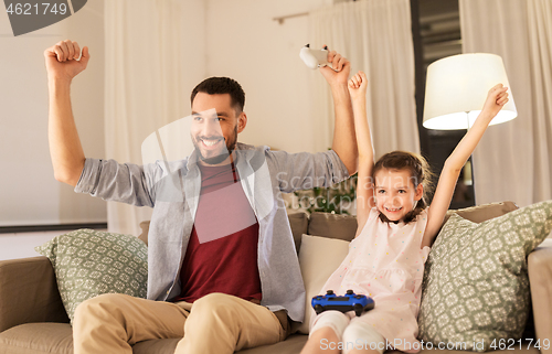 Image of father and daughter playing video game at home