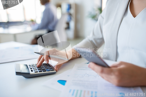 Image of businesswoman with calculator working at office