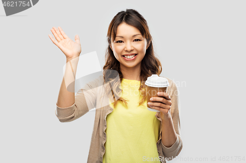 Image of happy asian woman drinking coffee and waving hand