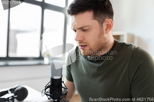 Image of male audio blogger with microphone broadcasting