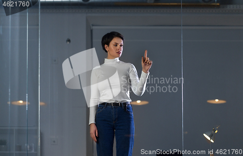 Image of businesswoman using glass wall at night office