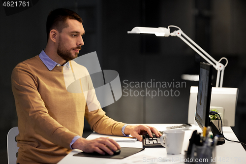 Image of man with computer working late at night office