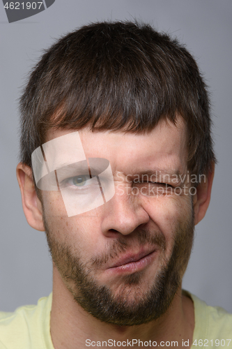 Image of Close-up portrait of a man of European appearance who squeezed his right eye tightly