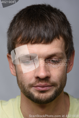 Image of Close-up portrait of a grieved downcast European-looking man who puffed out his cheeks