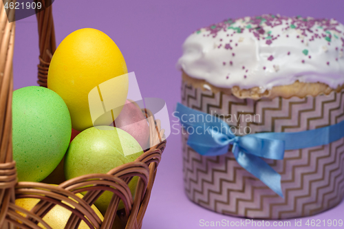 Image of Colored Easter eggs in a basket, Easter cake on the right in the background