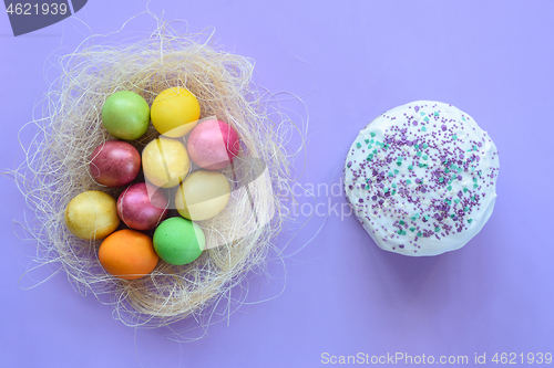 Image of Easter eggs in a makeshift nest on a purple background, next to Easter cake