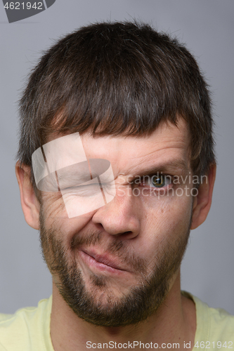 Image of Close-up portrait of a man of European appearance who squeezed his left eye tightly