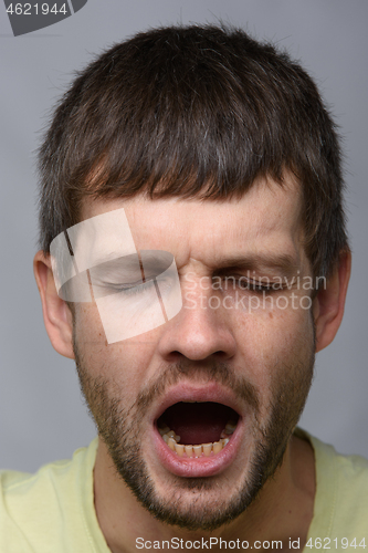 Image of Close-up portrait of a yawning man of European appearance