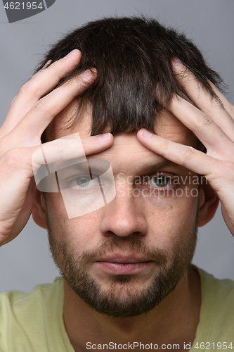 Image of Close-up portrait of a man of European appearance clutching his head with his hands