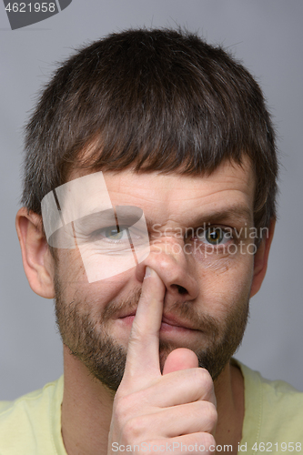 Image of Portrait of a man of European appearance, who put his finger in his nose, close-up