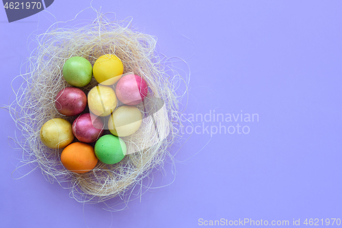 Image of Easter eggs in a makeshift nest on a purple background