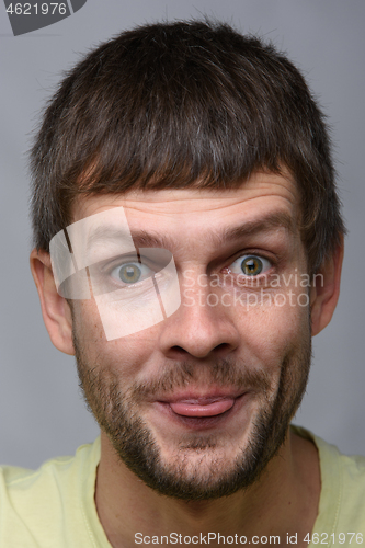 Image of Portrait of a cheerful man of European appearance showing tongue, close-up