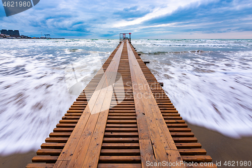 Image of Sea surf after sunset, a wooden pier goes into the distance