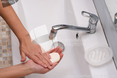 Image of Girl soaping her hands with soap in the washbasin