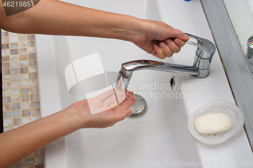 Image of The girl opens the handle of the mixer in order to wash her hands