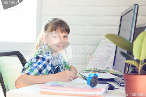 Image of Happy schoolgirl is studying at home and looked into the frame