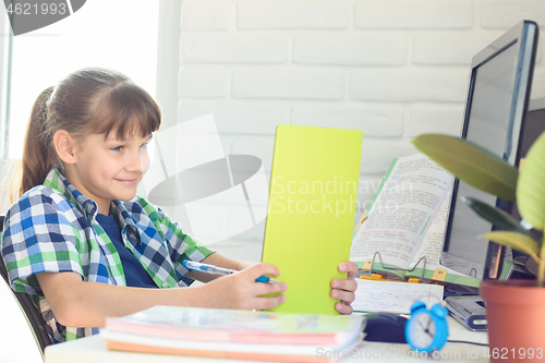 Image of Smiling schoolgirl cheerfully watches a video tutorial on a tablet computer