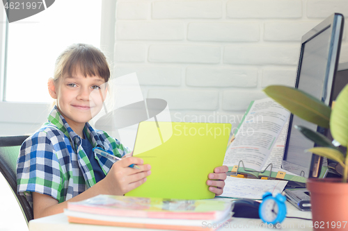 Image of A ten-year-old girl is studying remotely at home and cheerfully looked into the frame.