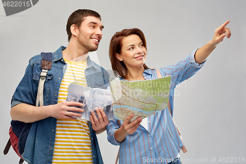 Image of happy couple of tourists with city guide and map