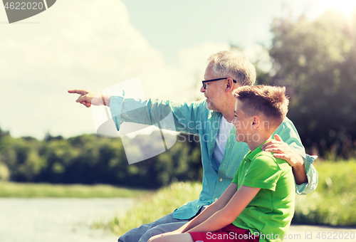 Image of grandfather and grandson sitting on river berth