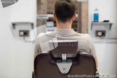 Image of man sitting in chair at barbershop or hair salon