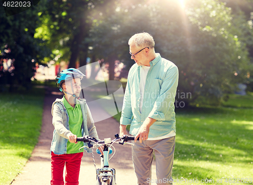 Image of grandfather and boy with bicycle at summer park