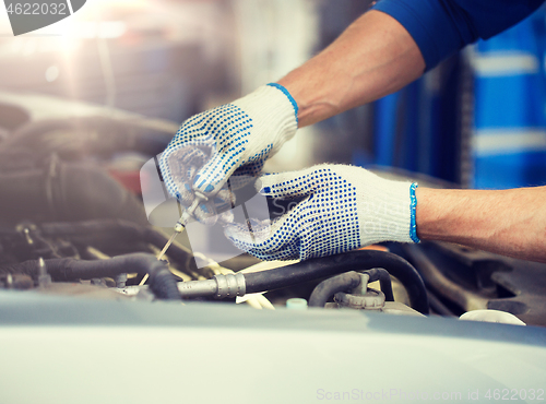 Image of mechanic with dipstick checking motor oil level